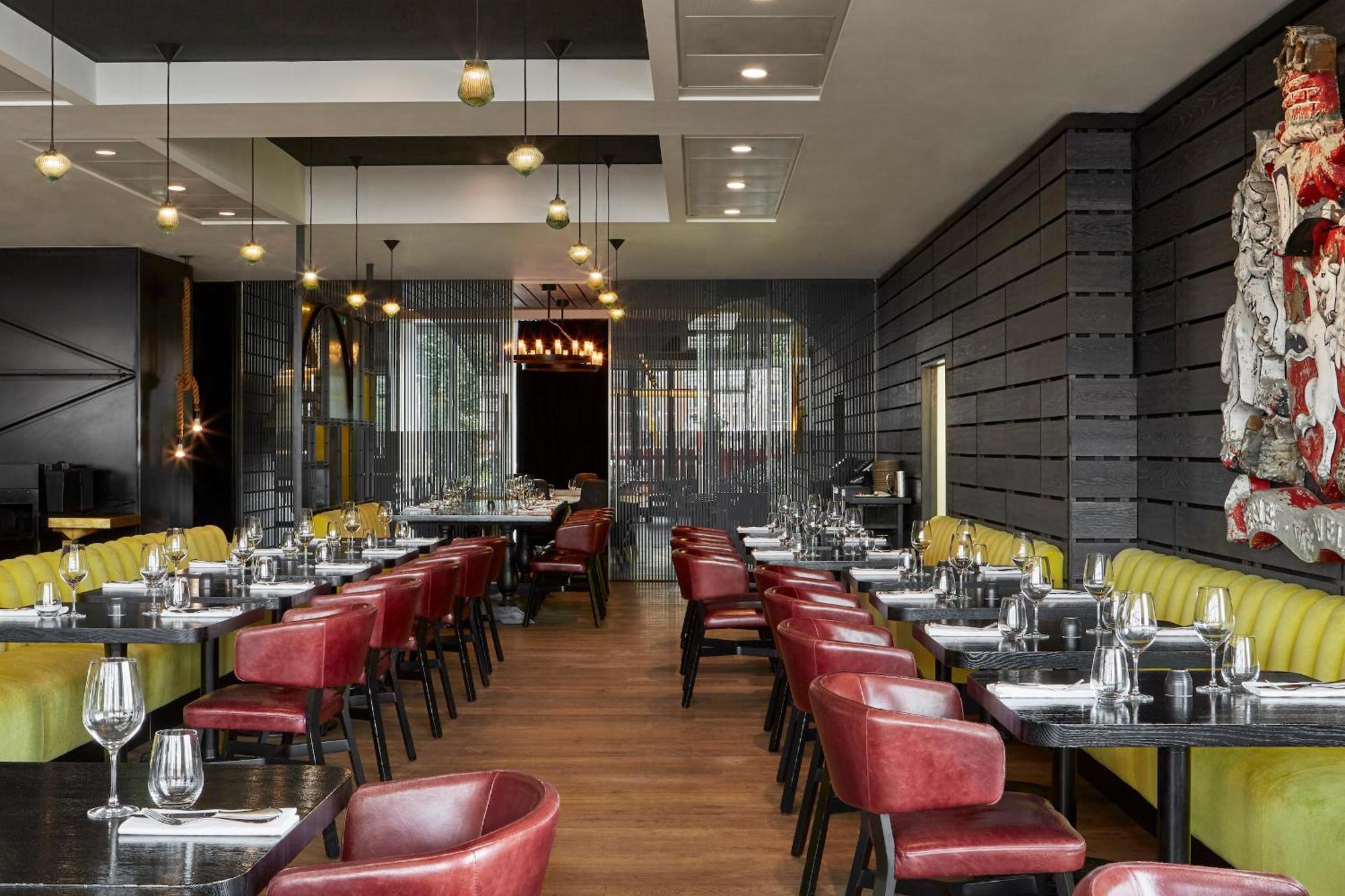 Sea Containers London Hotell Eksteriør bilde The photo shows an interior of a modern restaurant. It features a combination of wooden and metallic elements, with a sleek design. The tables are set with cutlery and glassware, indicating readiness for diners. There are red and yellow upholstered c