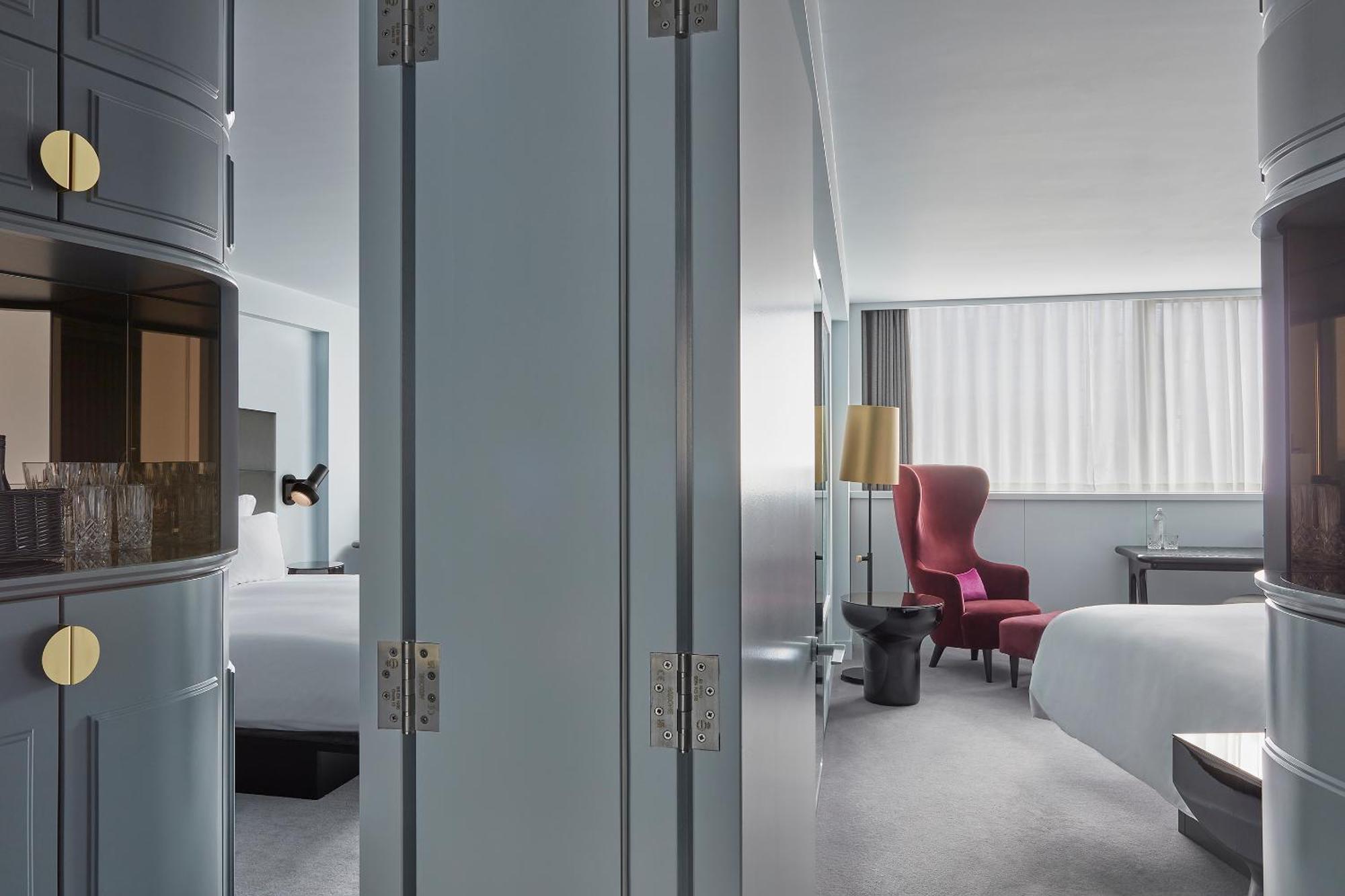 Sea Containers London Hotell Eksteriør bilde The photo shows an interior space that appears to be a modern hotel room. The room is divided by a pair of large, grey doors that are slightly ajar. To one side, there are elements that hint at a welcoming, spacious ambiance, such as a bed with white