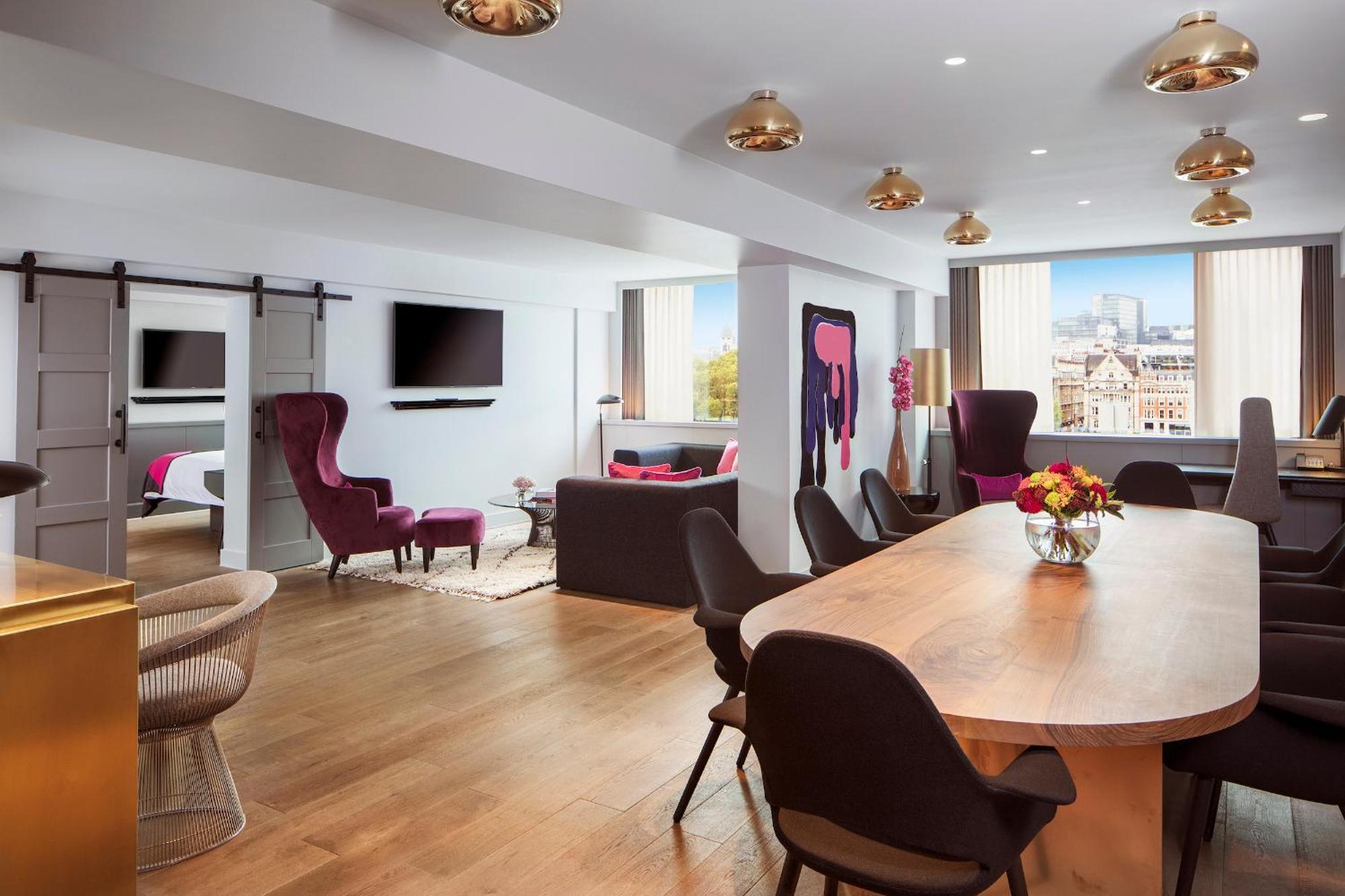 Sea Containers London Hotell Eksteriør bilde The photo shows a modern and stylish lounge or living area. It features a spacious layout with wooden flooring and large windows letting in natural light. 

On one side, there are two distinct seating areas: a cozy dark-colored sofa facing a televisi