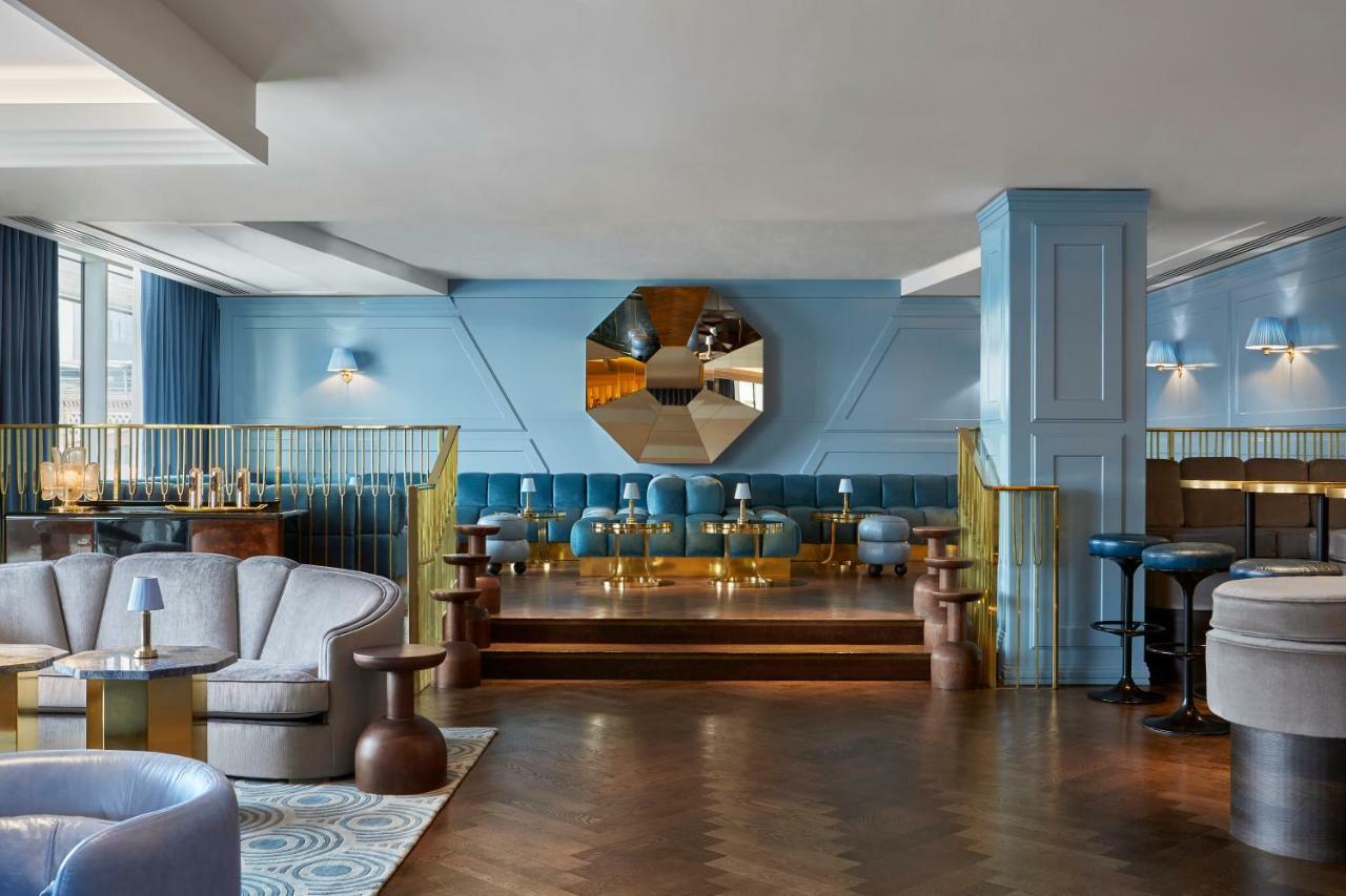 Sea Containers London Hotell Eksteriør bilde The photo shows a stylish and modern interior of a lounge or bar. The space features soft blue walls and various seating options, including plush armchairs and small tables. There is a prominent mirror that's octagonal in shape, adding a decorative e