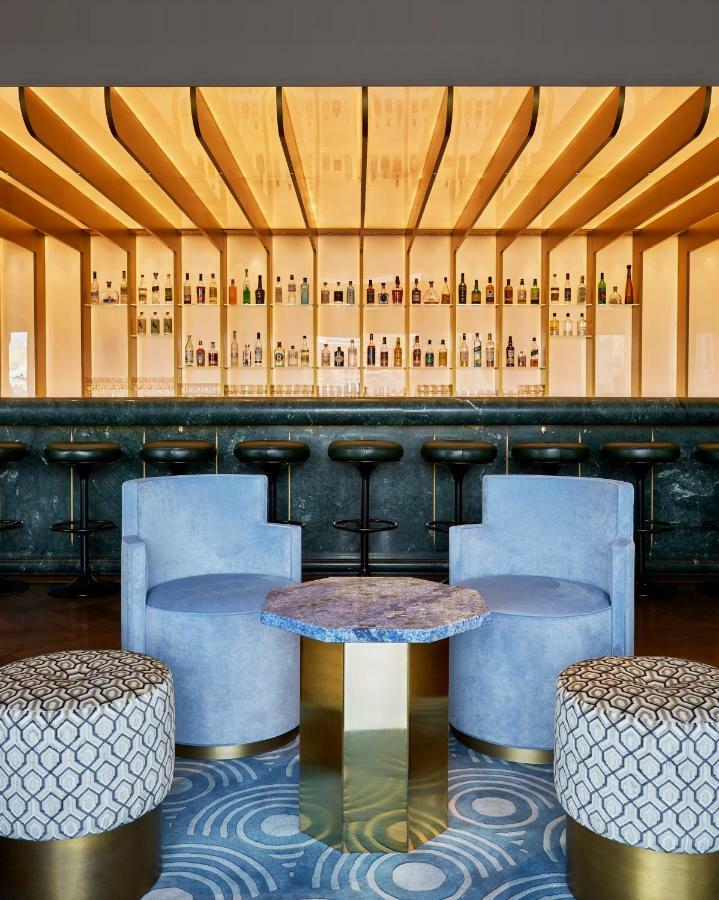 Sea Containers London Hotell Eksteriør bilde The photo showcases a modern bar interior. In the background, there is a long bar counter with various bottles displayed on shelves illuminated by soft lighting. The bar stools are sleek and black, positioned in front of the counter. In the foregroun