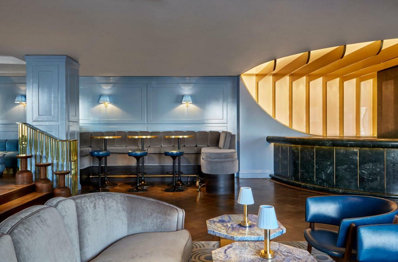 Sea Containers London Hotell Eksteriør bilde The photo shows an elegantly designed interior space, likely a bar or lounge. The area features a modern seating arrangement with a mix of comfortable sofas and bar stools. The walls are painted in a soft blue color, complemented by wooden accents an